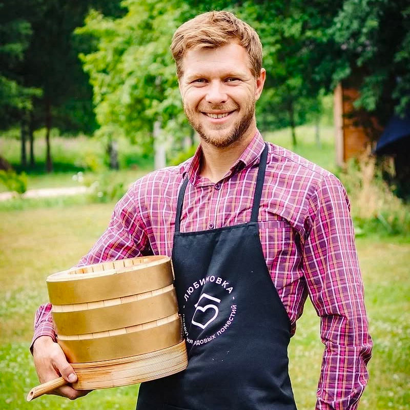 man holding a wooden oil press used for cold-pressed siberian cedar pine oil production