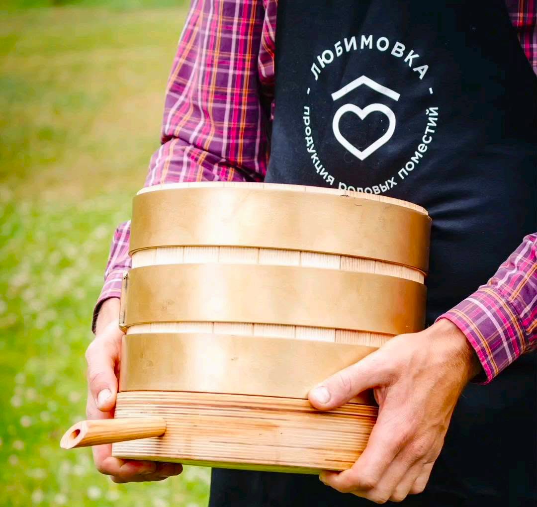 man holding a wooden oak oil press barrel used for making cold-pressed siberian cedar pine oil